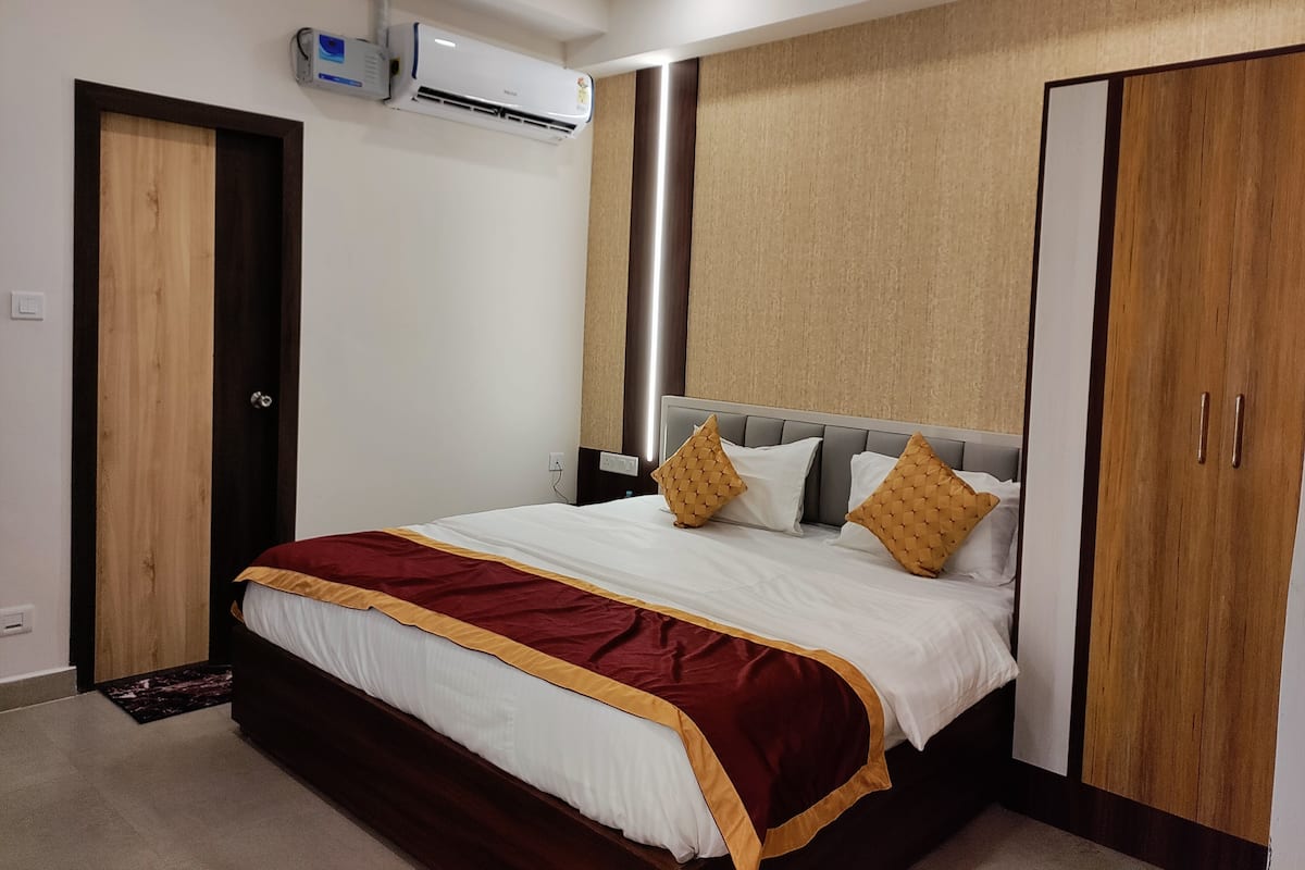 A hotel room with a bed, a wardrobe, and an air conditioning unit.
