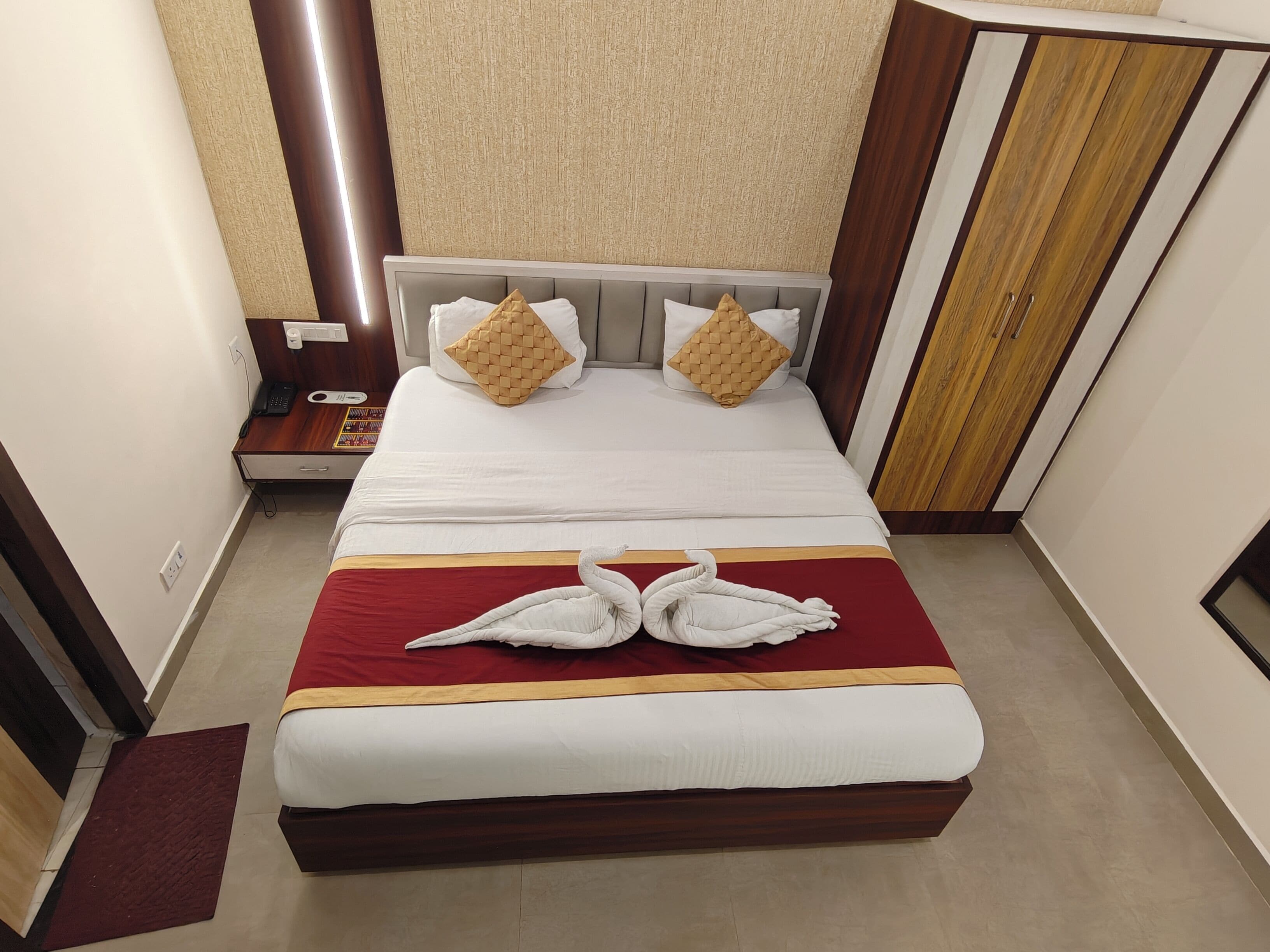 A hotel room with a bed, a nightstand, a telephone, and a wardrobe.