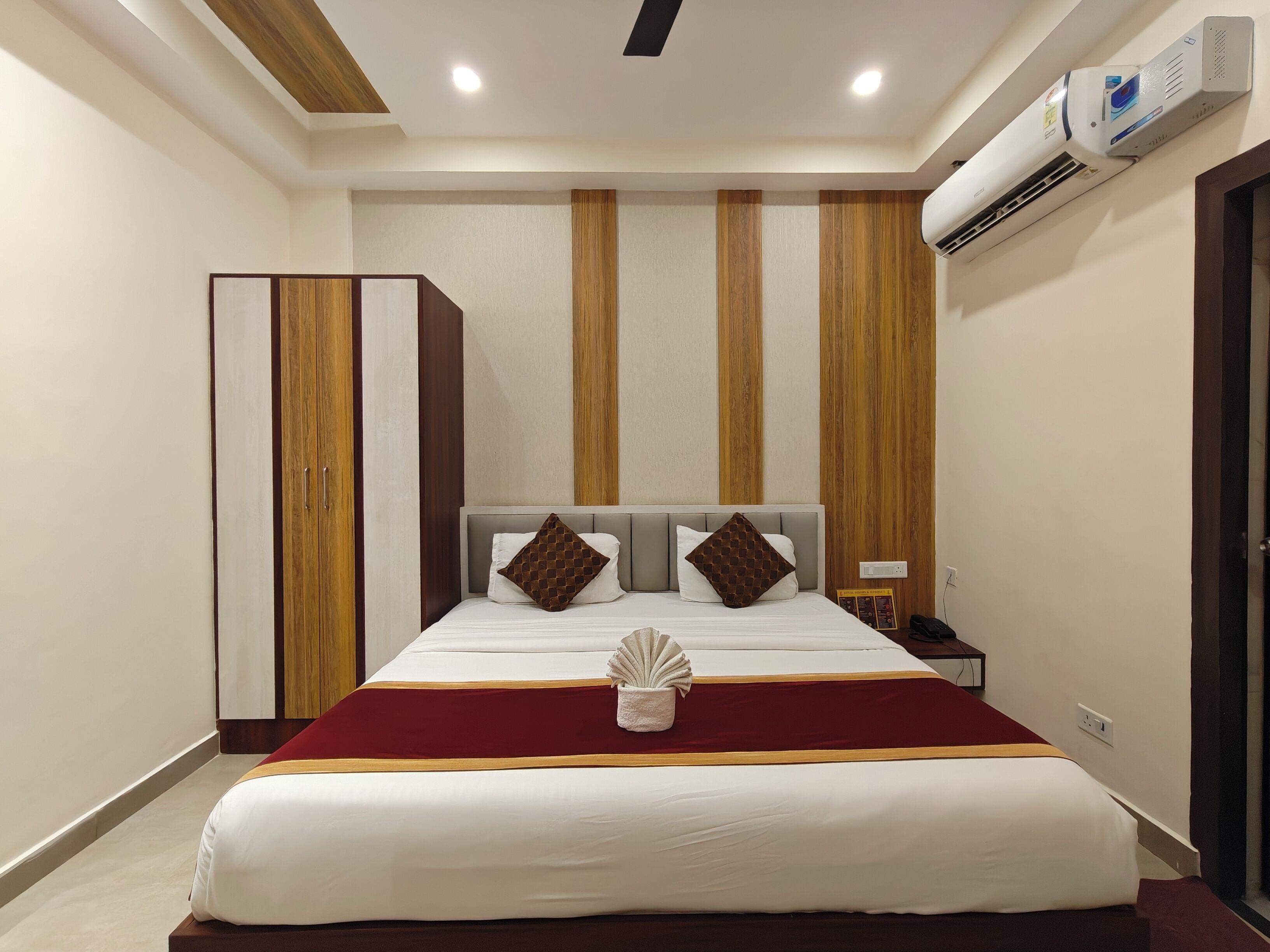 Quarto de hotel com cama, mesa de cabeceira e guarda-roupa.