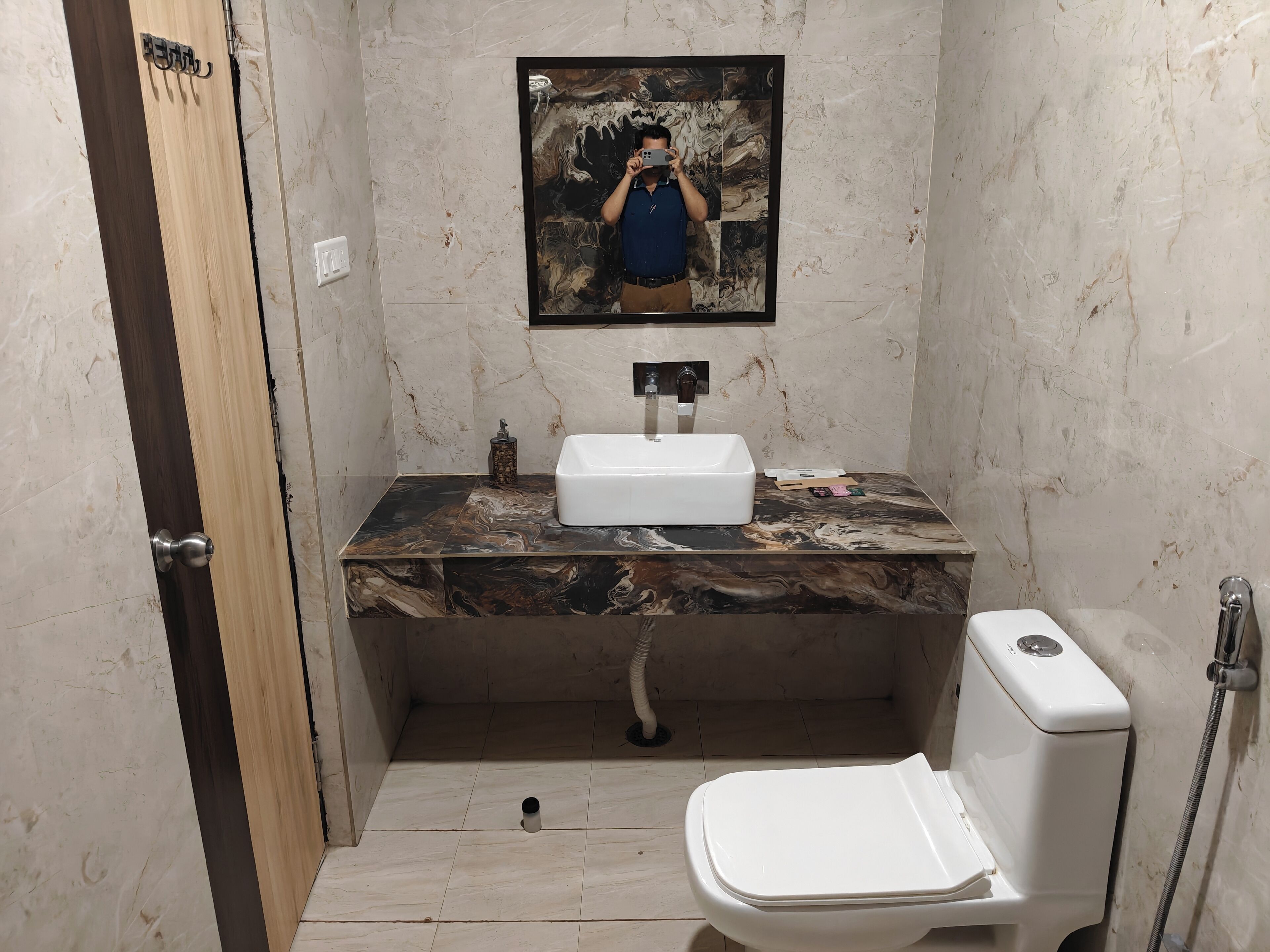 Un baño con tocador de mármol, lavamanos, inodoro y espejo.