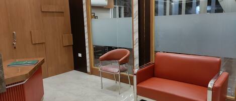 A reception area with a wooden desk, a red leather sofa, and a glass partition.