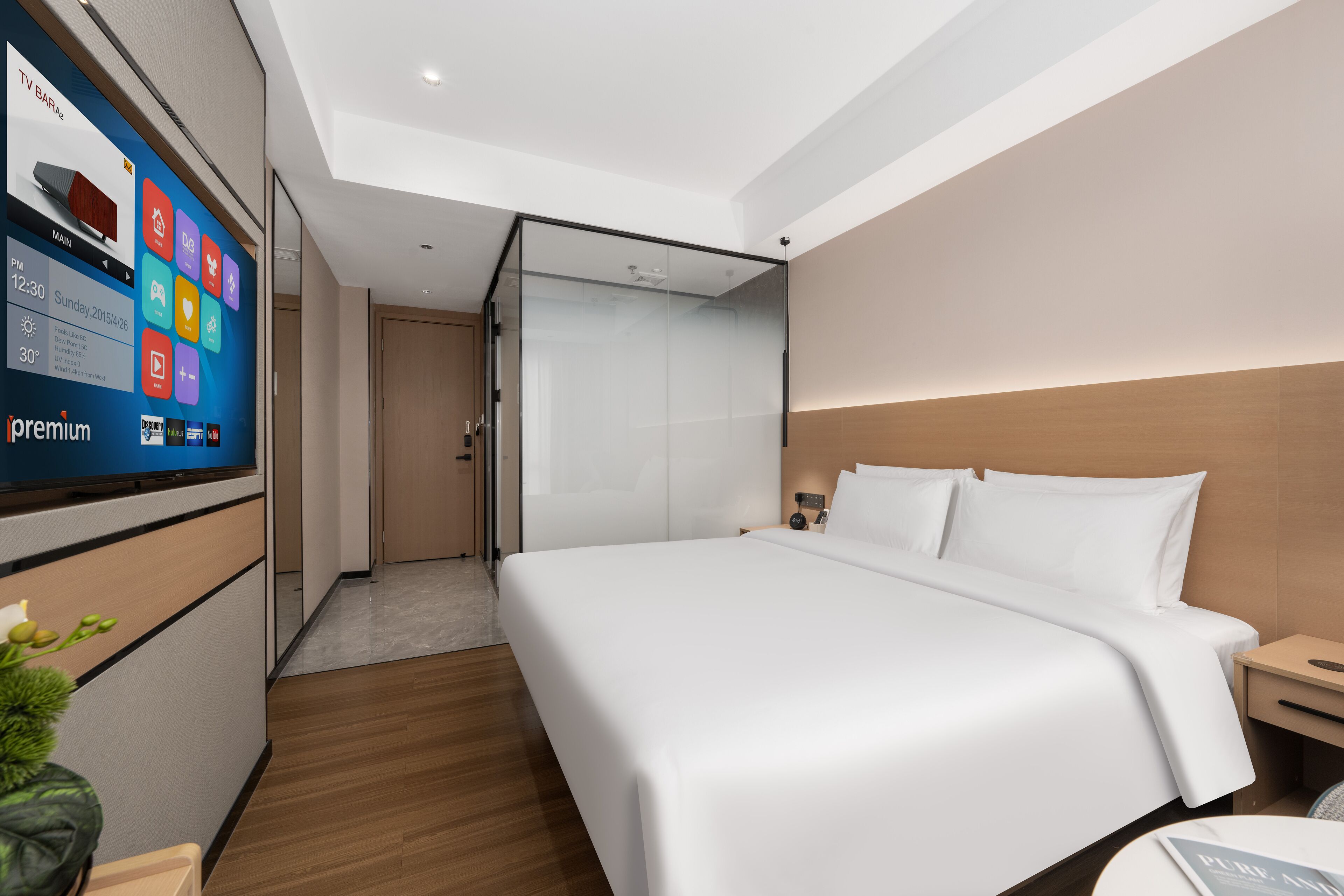 A modern hotel room with a large bed, a TV on the wall, and a wooden floor.