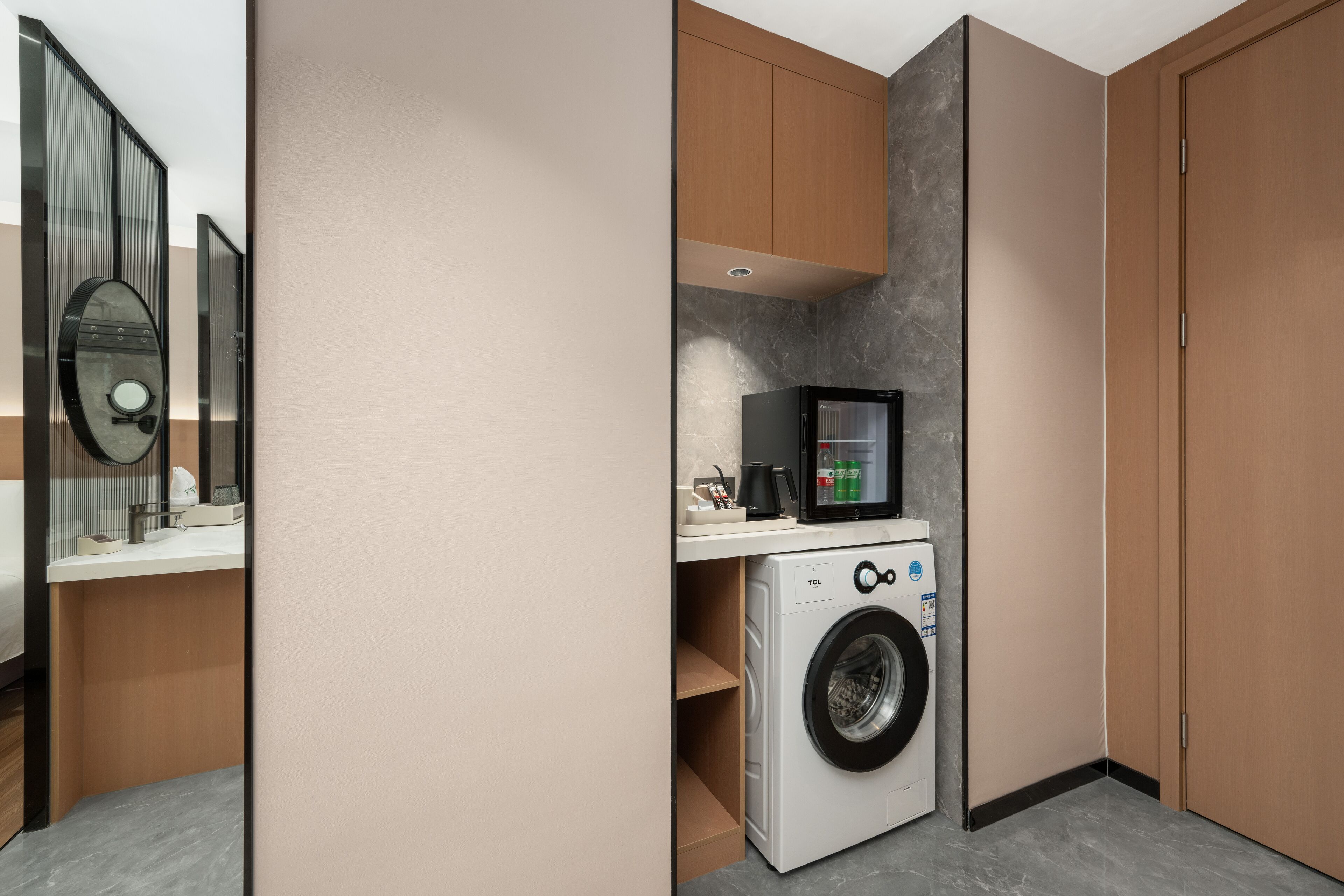 A compact laundry room with a washing machine, a small refrigerator, and a microwave.