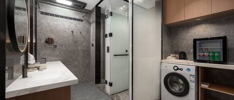 Un baño moderno con lavamanos de mármol, cabina de ducha de vidrio y lavadora integrada.