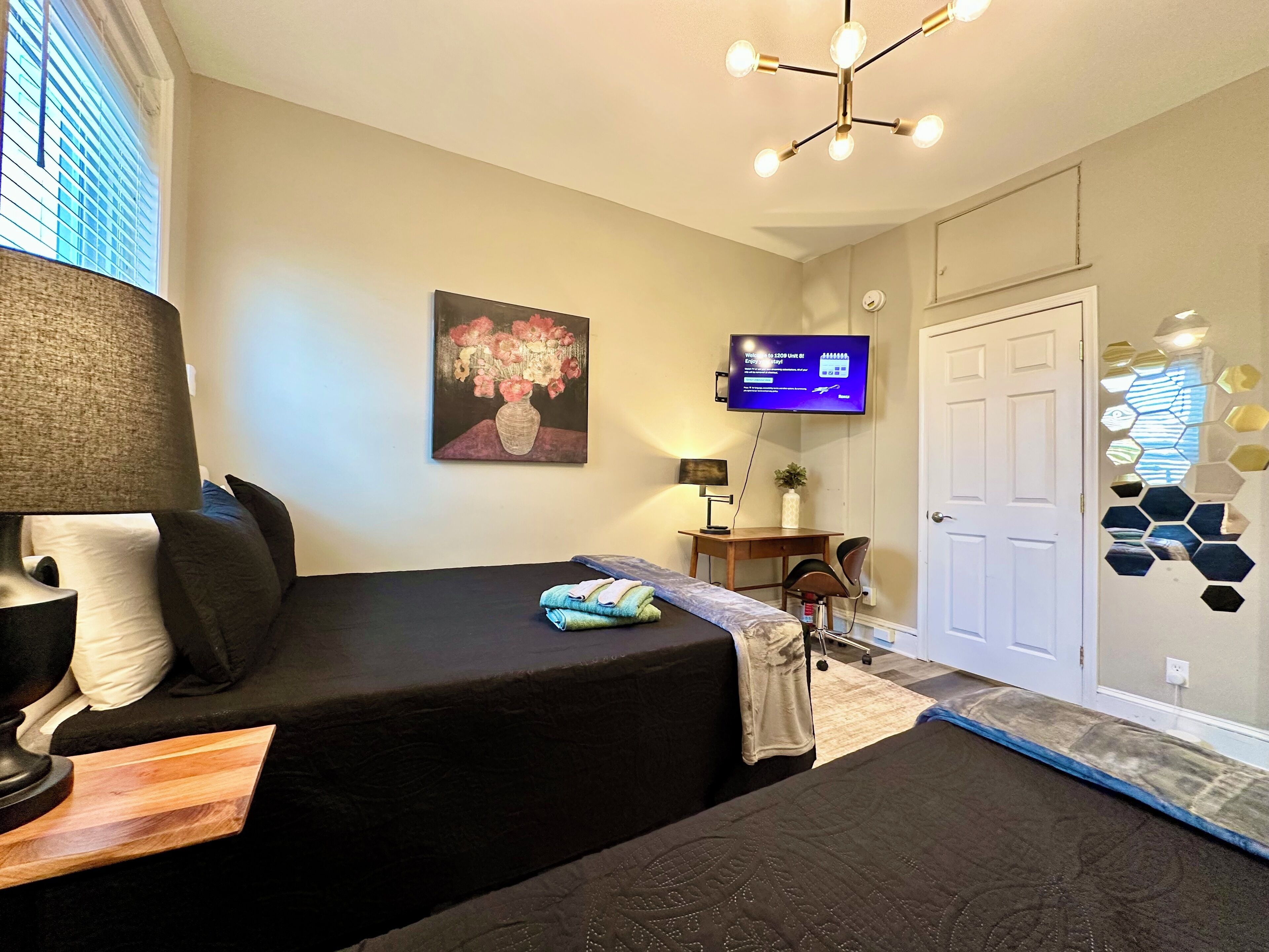 Una habitación de hotel con cama, escritorio, televisor y puerta.