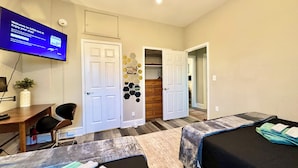 A hotel room with two beds, a desk with a chair, a television, and a closet.