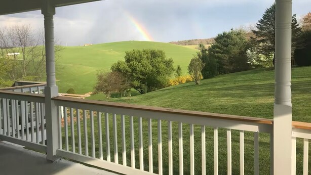 A porch with a view of a green field and a rainbow. - Panoramic Picturesque Home in Blue Ridge Mtns (Max Meadows)