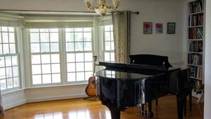 A spacious room with a grand piano, a bookshelf, and a guitar. - Panoramic Picturesque Home in Blue Ridge Mtns (Max Meadows)