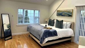 Un dormitorio con cama, ventana, un cuadro y un espejo.