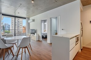 Enjoy a spacious living area with a dining table, kitchenette, and bedroom, offering a city view.
