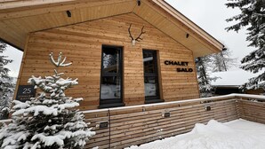Un chalet en bois avec une enseigne indiquant « CHALET SALO » et un panneau de stationnement indiquant « 25 CHALET SALO ».