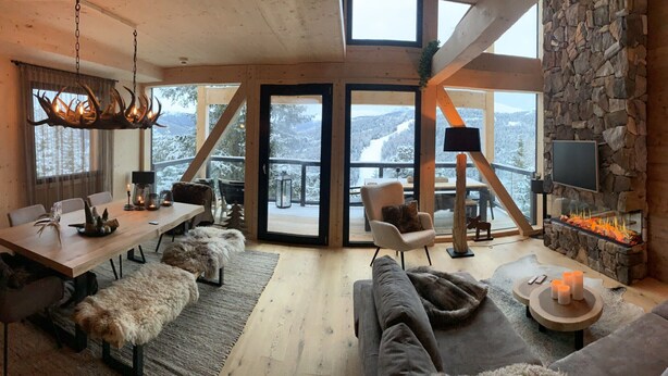 Un intérieur chaleureux avec un mur en pierre, une cheminée, un coin repas et un canapé.