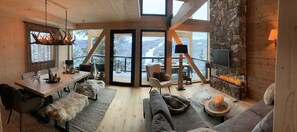 A cozy interior with a stone wall, a fireplace, a dining area, and a sofa. - Chalet in Turrach With Sauna and Terrace (Stadl-Predlitz)