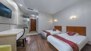Habitación de hotel con dos camas, un escritorio, una silla y un televisor montado en la pared.
