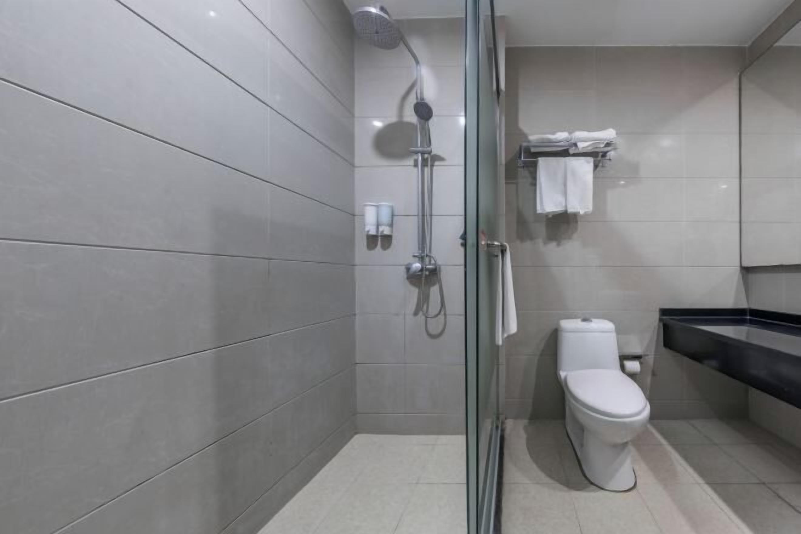 A modern bathroom with a glass shower enclosure, a toilet, and a black countertop.