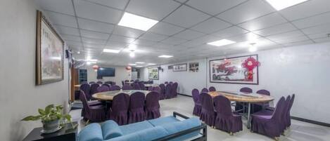 A conference room with multiple tables and chairs, a sofa, and framed artwork on the walls.