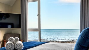 Una habitació d'hotel amb un llit, una cadira i vista al mar.
