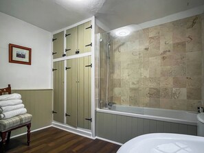 A bathroom with a bathtub, a wooden bench with towels, and a framed picture on the wall. - 3 bedroom accommodation in Ashbourne (Ashbourne)