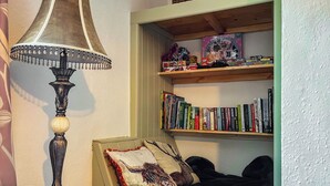 Ein Zimmer mit einem Bett, einer Lampe und einem Bücherregal mit Büchern und Spielzeug.