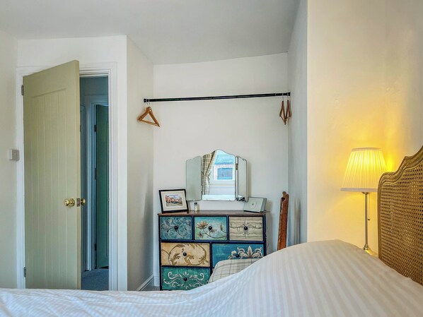 Un dormitorio con cama, cómoda con cajones, espejo y lámpara colgante.