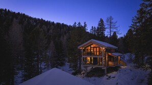 Eine Holzdiele mit Balkon, umgeben von Schnee und Bäumen.