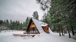 Eine Holzhütte mit geneigtem Dach und einer Veranda mit einer Bank.