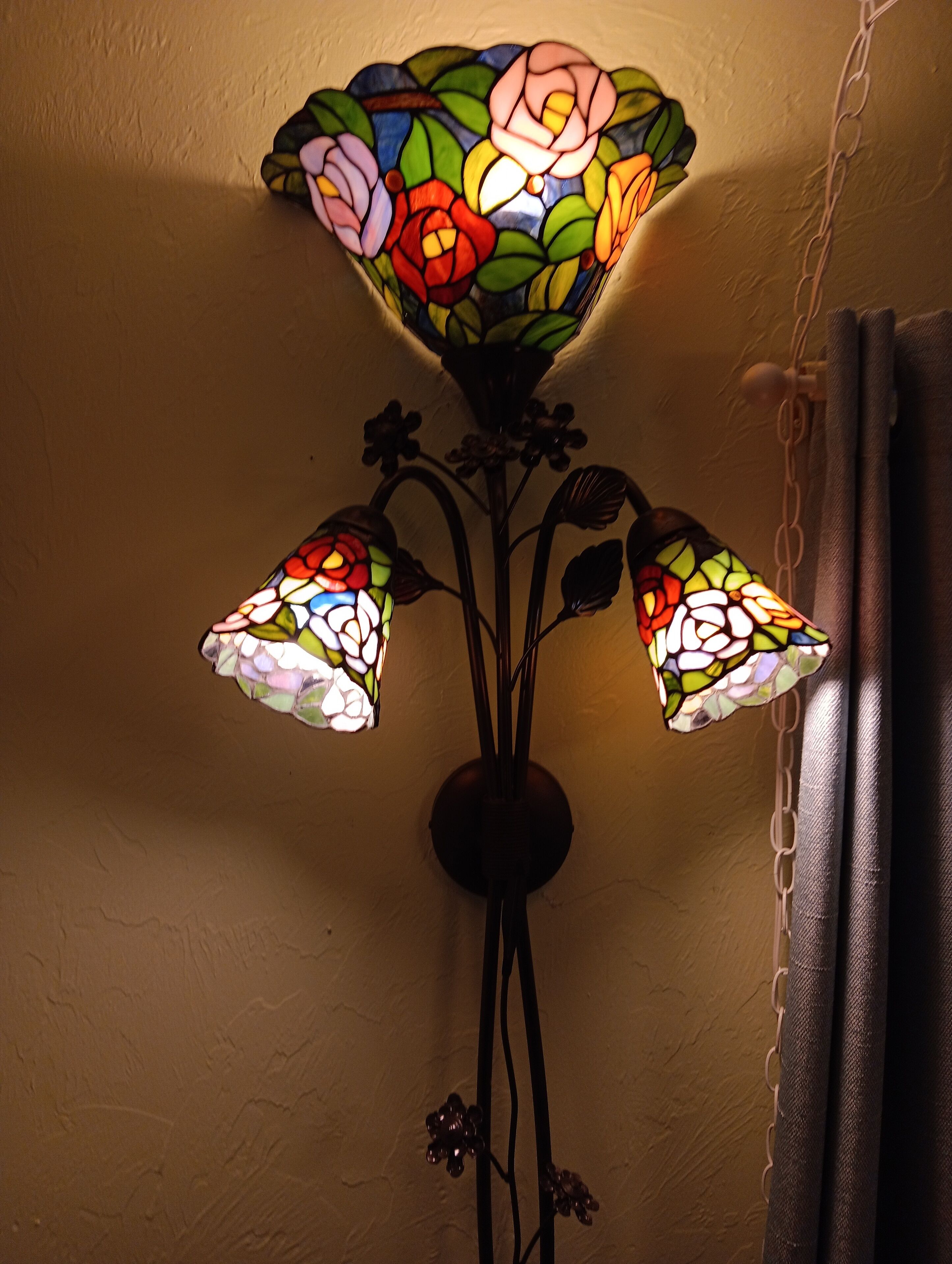 A wall-mounted stained glass lamp with three glass shades.