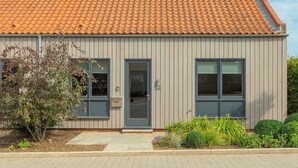 Un edificio moderno con techo de tejas, dos puertas y un pequeño jardín.