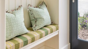 Asiento junto a la ventana con cojines estampados y uno a rayas.