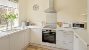 Una cocina moderna con horno empotrado, microondas y campana extractora de acero inoxidable.