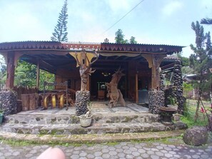 A covered entrance with stone steps, wooden pillars, and a deer statue. - Aurora Living Merapi Jogja (Pakem)