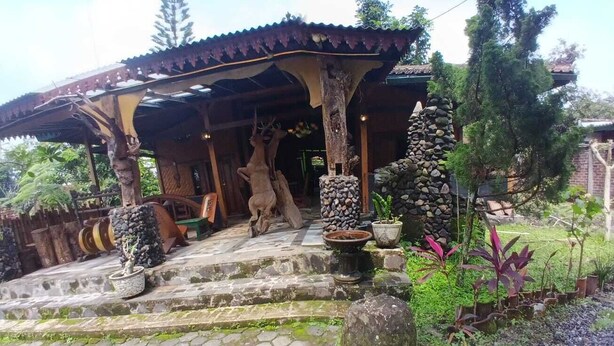 A traditional wooden structure with a tiled roof, stone steps, and potted plants. - Aurora Living Merapi Jogja (Pakem)