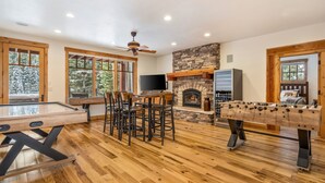A spacious room with a pool table, a foosball table, and a fireplace.