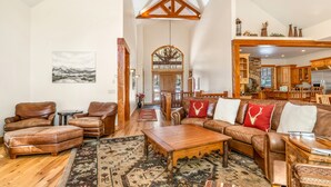 A spacious living room with leather furniture, a wooden coffee table, and a large rug.