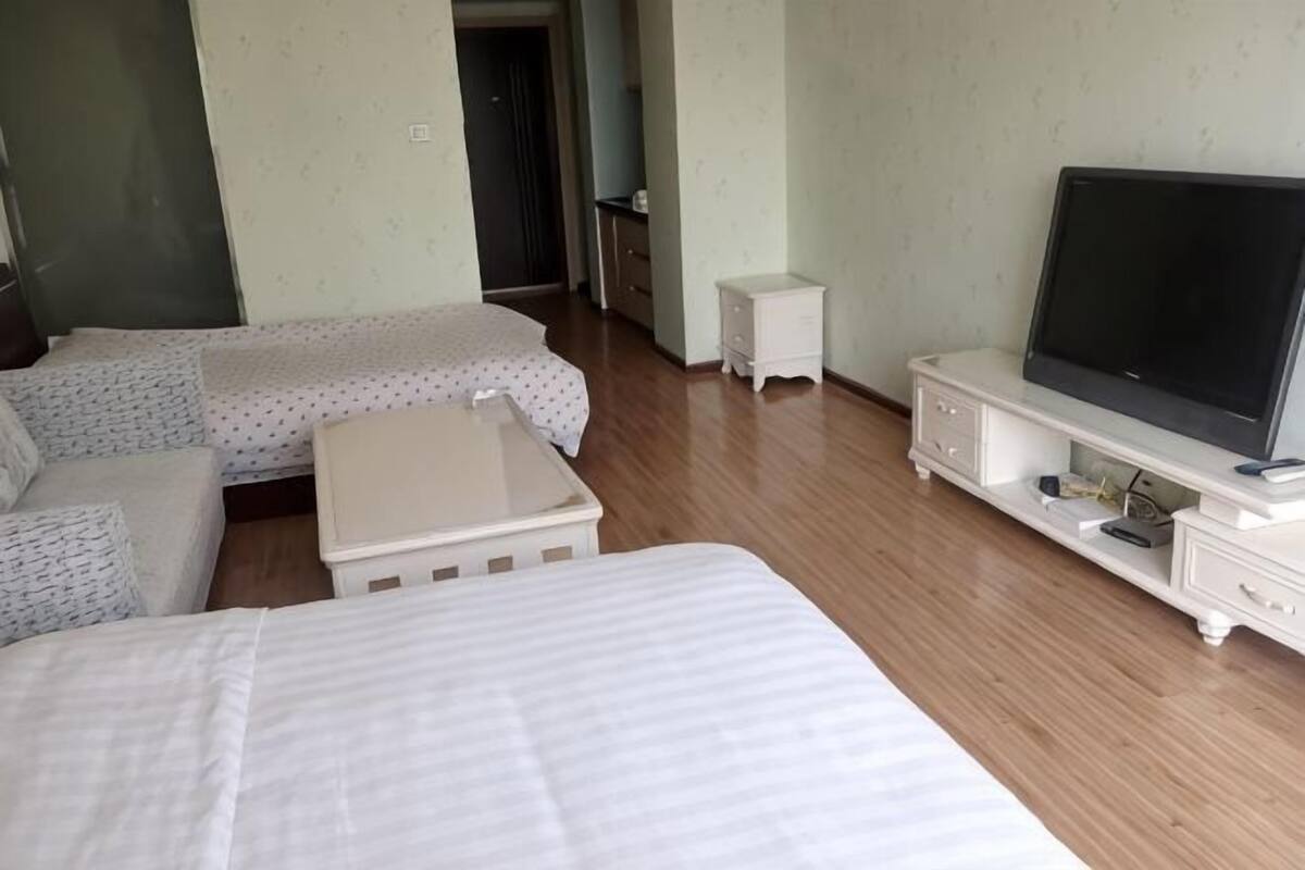 Une chambre d’hôtel avec un lit, un canapé, une télévision et une petite table.