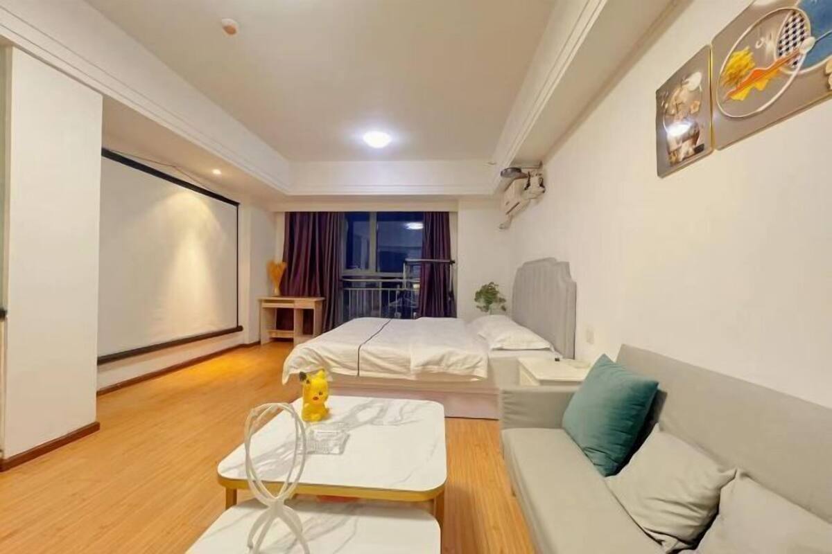 Une chambre d’hôtel avec un lit, un canapé, une petite table et une fenêtre avec des rideaux.