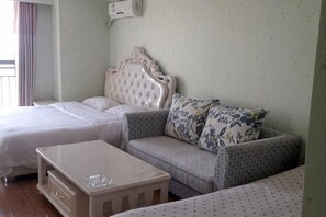 Una habitación de hotel con una cama, un sofá, una mesita y un aire acondicionado de pared.