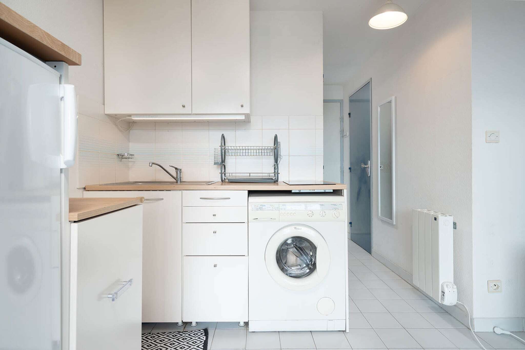A compact kitchen with a washing machine, a sink, and a countertop.