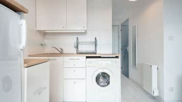 A compact kitchen with a washing machine, a sink, and a countertop.