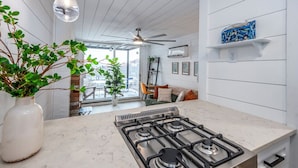 A modern kitchen with a gas stove, white cabinets, and a large window overlooking a balcony. - Mt Adams Studio+Steps to Art Museum+Fully Equipped+Stellar City Views+Fast Wifi (Cincinnati)
