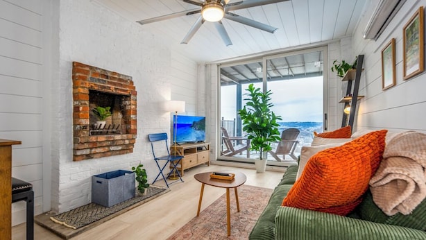 A cozy living room with a fireplace, a television, and a view of the ocean through large windows. - Mt Adams Studio+Steps to Art Museum+Fully Equipped+Stellar City Views+Fast Wifi (Cincinnati)