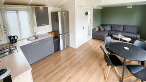 Un espace de vie compact comprenant un coin cuisine, un coin repas et un espace détente avec un canapé et des tables.