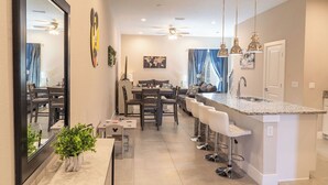 Una cocina moderna con una isla central, taburetes de bar e iluminación colgante.