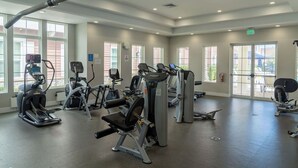 Un gimnasio con diversa maquinaria de cardio y entrenamiento de fuerza, ventanas amplias y un interior moderno y limpio.