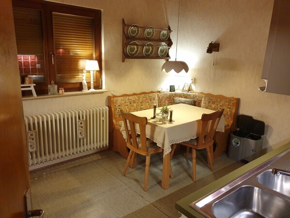 A cozy dining area with a wooden table and chairs, a radiator, and a wall-mounted shelf with decorative plates. - House for 8 persons. 5 bedrooms, 2 bathrooms, 3 toilets with garage/garden. (Willingen (Upland))