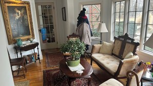 A cozy living room with a wooden floor, a patterned rug, a green potted plant, a wooden chair, and a sofa. - Spacious room in Tudor home overlooking the Maumee river near Metro Parks. Wifi (Grand Rapids)