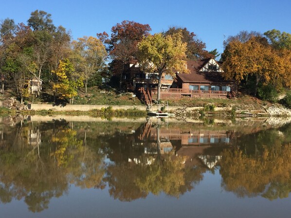 Propiedad frente al lago con casa, muelle y reflejo en el agua.