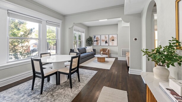 A modern living room with a dining area, large windows, a sofa, and a coffee table.