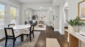 A spacious dining area with a round table and chairs, a sofa, and a coffee table in the background.