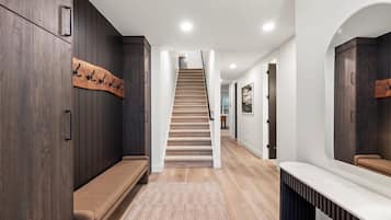 Un couloir moderne avec un banc en bois, un porte-manteau et un escalier menant à une autre pièce.